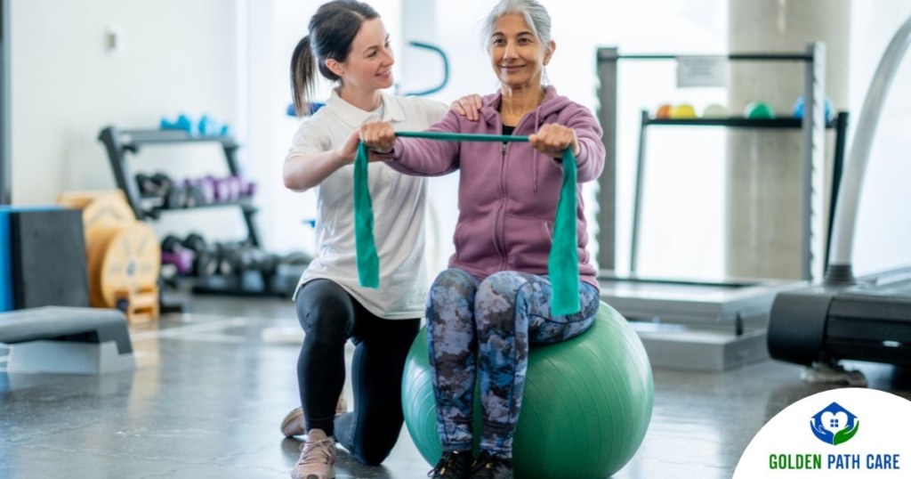 A care provider helps an older woman exercise with a resistance band and an exercise ball, representing how exercise can help with senior fall prevention.